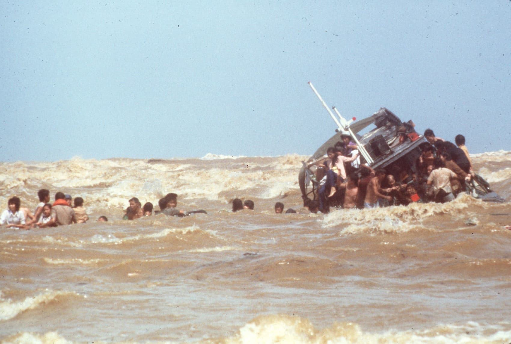 Vietnamese refugees scramble from a sinking boat which they beached at Kuala Trengganu, Malaysia, in December 1978. (AP)