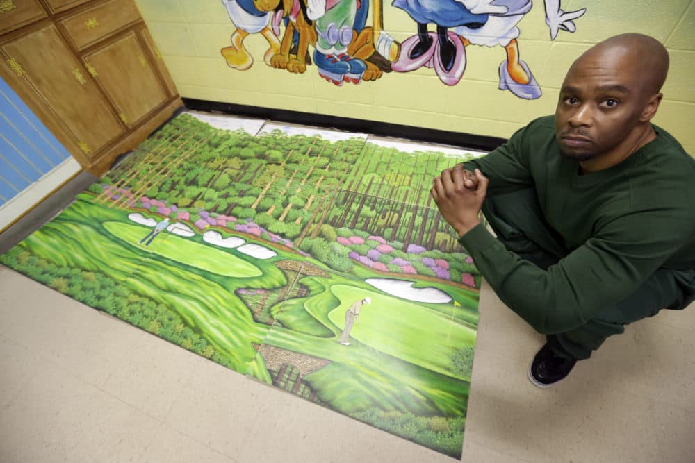 Valentino Dixon poses in 2013 with golf art he created while serving time for a murder he didn't commit. (AP/David Duprey)