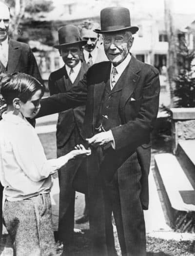 U.S. philanthropist and oil magnate John D. Rockefeller gives a coin to a child. (AP Photo)