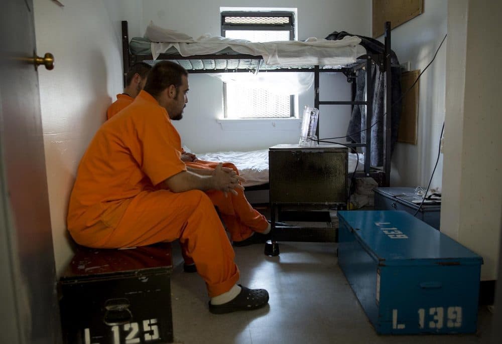 Two patients at MASAC in Plymouth sit in one of the facility's small bedrooms in 2017. The rooms former cells with metal mesh on the windows and bunk beds. (Robin Lubbock/WBUR)