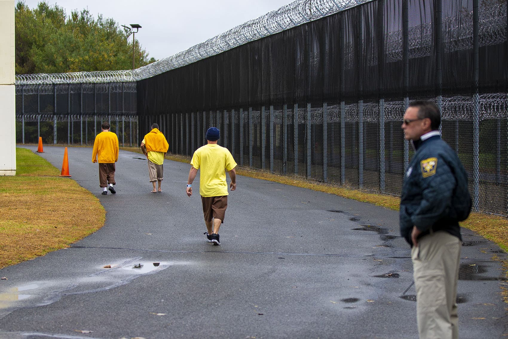 Men who have been civilly committed to the addiction treatment unit at the Hampden County Jail in Ludlow walk around a fenced-in path to get some exercise. (Jesse Costa/WBUR)