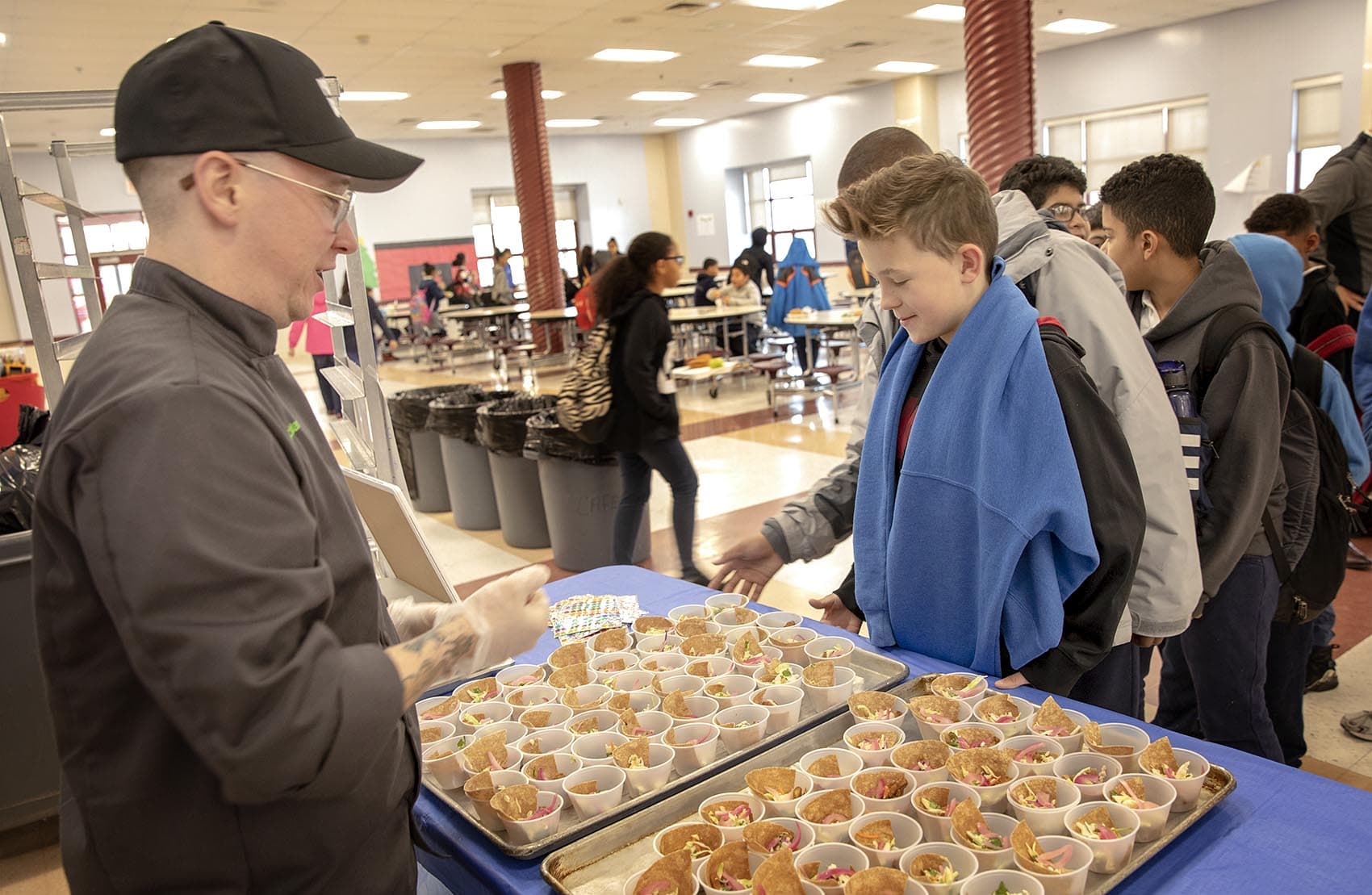 Students at the Parthum School in Lawrence line up to try chef Sam Icklan's Korean chicken tacos. (Robin Lubbock/WBUR)