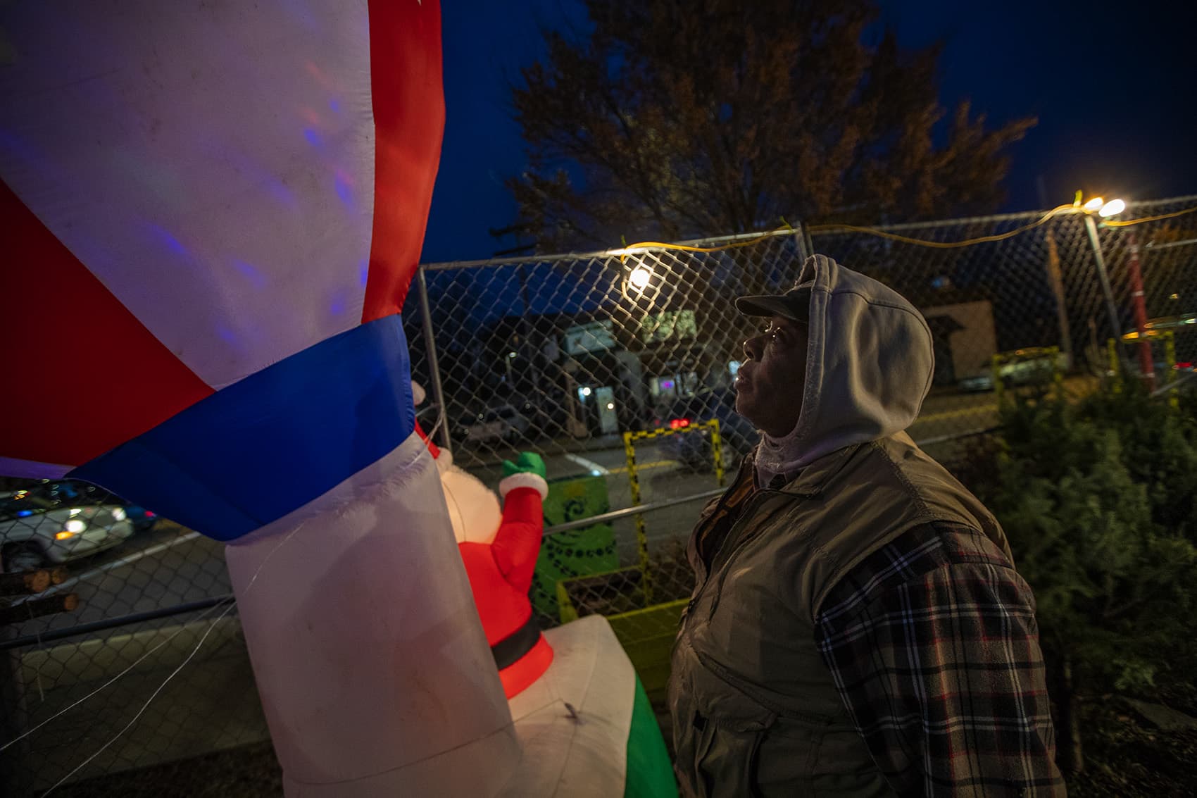 Dannie Kelly looks up to check the Santa balloon, which is persistently falling over because of the wind. (Jesse Costa/WBUR)