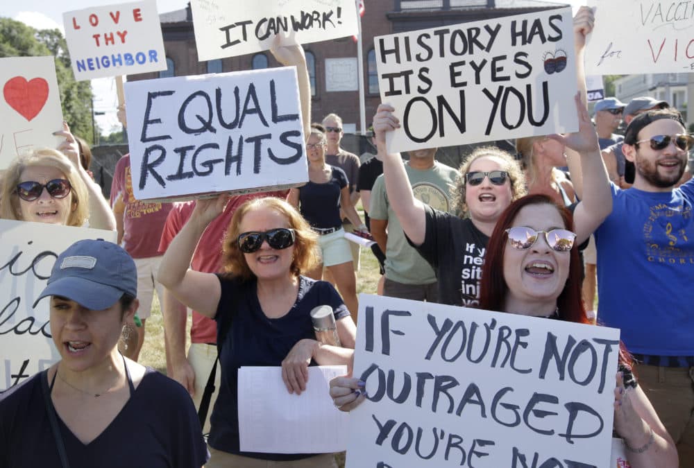 Nicole DePace, of Quincy, Mass., front left, and Denise Ashworth, of New Bedford, Mass., front right, join with other demonstrators as they display placards and chant slogans during a protest, Sunday, Aug. 13, 2017, in Plymouth, Mass. The protest was held to denounce hatred and racism in response to a nationalist rally that spiraled into deadly violence in Charlottesville, Va., Saturday, Aug. 12, 2017. (Steven Senne/AP)