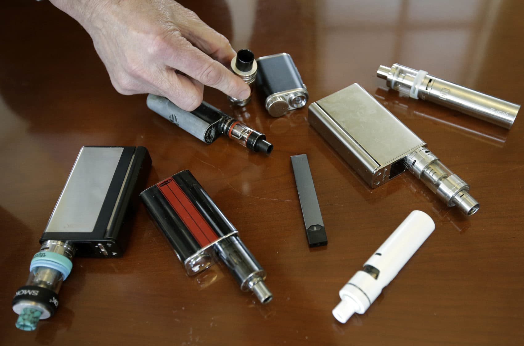 Marshfield High School Principal Robert Keuther displays vaping devices that were confiscated from students in such places as restrooms or hallways at the school in Marshfield, Mass. Health and education officials across the country are raising alarms over wide underage use of e-cigarettes and other vaping products. The devices heat liquid into an inhalable vapor that's sold in sugary flavors like mango and mint, and often with the addictive drug nicotine. (Steven Senne/AP)