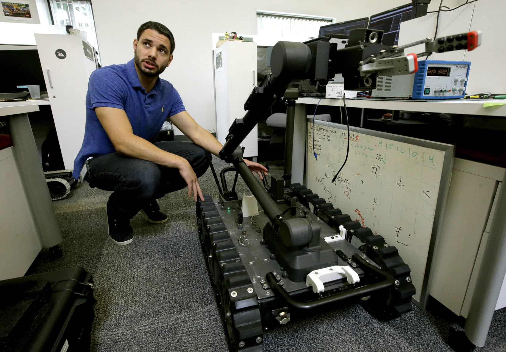 In this Aug. 28, 2018 photo, software engineer Nicholas Otero, of Woburn, Mass., speaks with a colleague about features on a Centaur robot, right, at Endeavor Robotics in Chelmsford, Mass. The Army is looking for a few good robots. These robots won’t fight, at least not yet. But they will be designed to help the men and women who do. The companies making them are waging a different kind of battle. At stake is a contract worth almost half a billion dollars for 3,000 backpack-sized robots that can defuse bombs and scout enemy positions. (Steven Senne/AP)