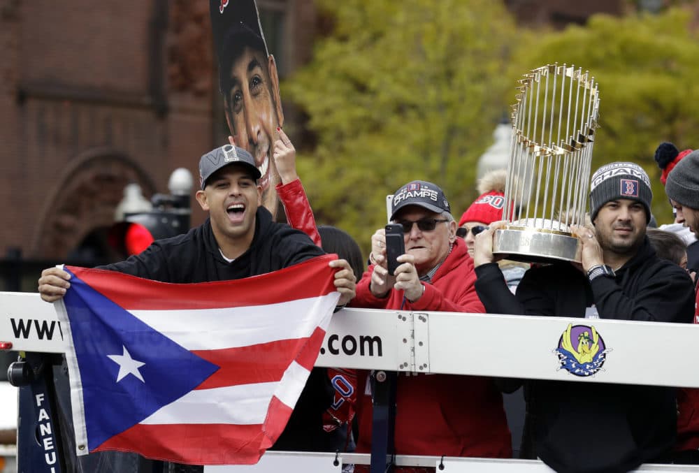 Boston Red Sox manager Alex Cora, left, waves the flag of Puerto Rico as coach Ramon Vazquez holds the championship trophy during a parade to celebrate the team's World Series championship over the Los Angeles Dodgers, Wednesday, Oct. 31, 2018, in Boston. (Elise Amendola/AP)