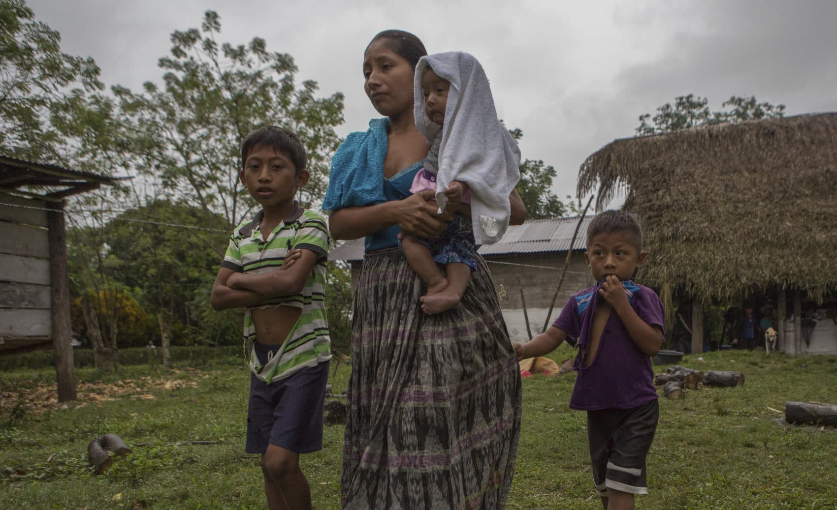 Claudia Maquin, 27, walks with her three children, Abdel Johnatan Domingo Caal Maquin, 9, left, Angela Surely Mariela Caal Maquin, 6 months, middle, and Elvis Radamel Aquiles Caal Maquin, 5, right, as they leave the house of Domingo Caal Chub, Claudia's father-in-law, in Raxruha, Guatemala, Saturday, Dec. 15, 2018. (Oliver de Ros/AP)