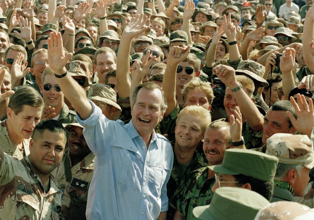 In this Nov. 22, 1990 file photo, President George Bush poses with soldiers during a stop at an air base in Dhahran, Saudi Arabia. (J. Scott Applewhite/AP)