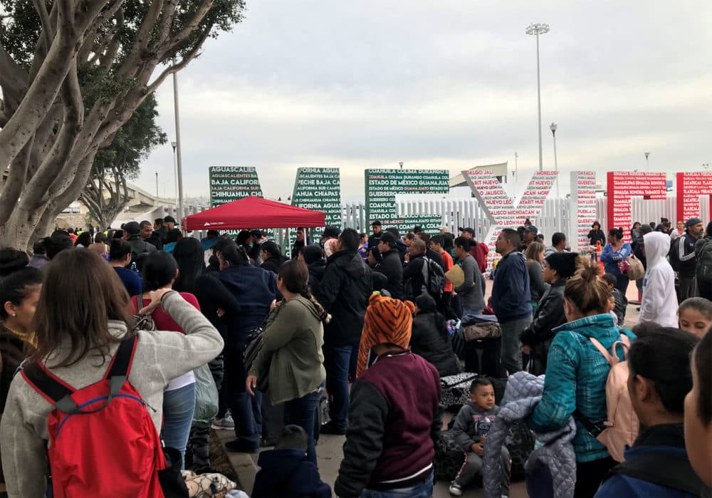 Families wait at &quot;El Chaparral,&quot; a border crossing near San Ysidro, California, to hear which names are called from the asylum waitlist. (Shannon Dooling/WBUR)