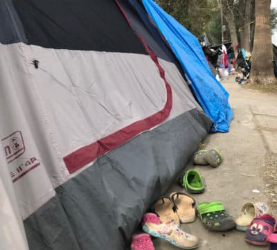 Shoes are lined up outside a tent near the Benito Juárez soccer stadium in Tijuana. There are an estimated 500 people, mostly from Central America, living in tents. (Shannon Dooling/WBUR)