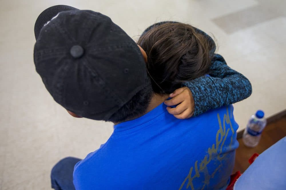 A young migrant family waits for the arrangements for their bus at Catholic Charities in McAllen, Texas. (Jesse Costa/WBUR)