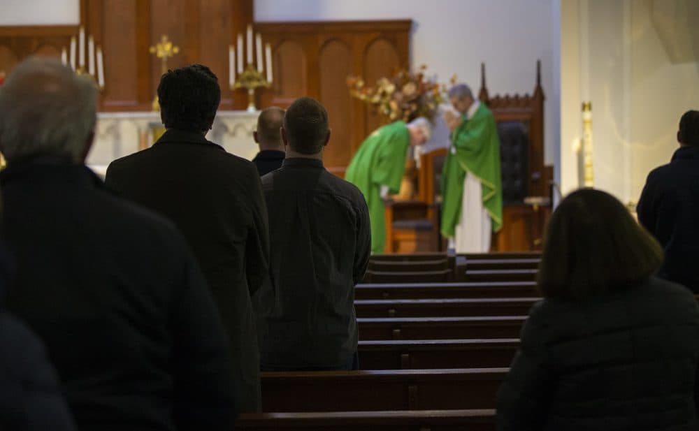 Parishioners stand in pews at Shrine of Our Lady of Good Voyage in the Seaport. (Jesse Costa/WBUR)