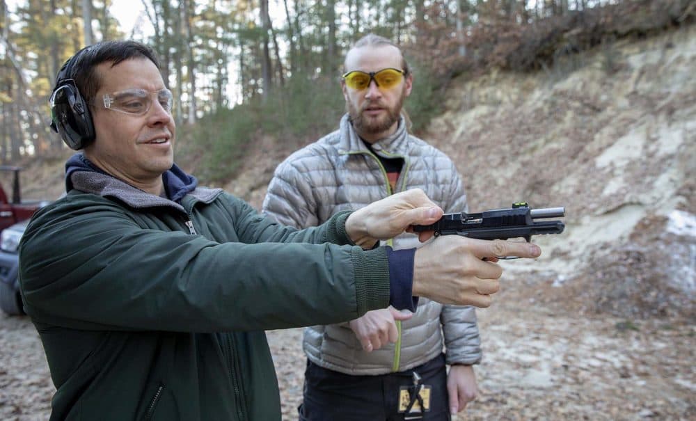 Under the watchful eye of instructor Aaron Grossman, Sergio Perez loads his first round into the chamber of a .22 pistol. (Robin Lubbock/WBUR)