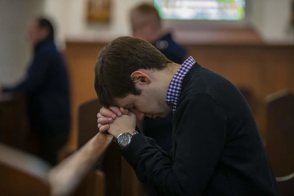 A young man prays in a pew at Shrine of Our Lady of Good Voyage in the Seaport. (Jesse Costa/WBUR)