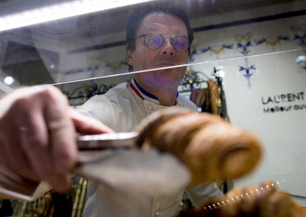 Laurent Duchêne, who has been decorated as one of France's top pastry chefs, replenishes croissants in a case at his Boutique in the 13th arrondissement on Nov. 12, 2018 in Paris. (Pete Kiehart for Here &amp; Now)