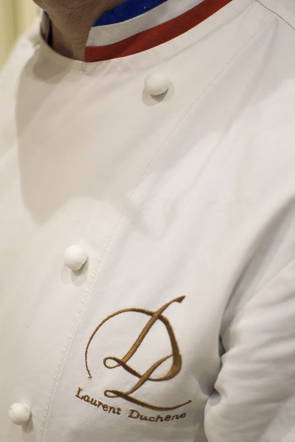 Laurent Duchne, who has been decorated as one of France's top pastry makers, poses for a photo at his boutique in the 13th Arrondissement on Nov. 12, 2018 in Paris. The tricolor collar on his jacket denotes his status as a Meilleur Ouvrier de France. (Pete Kiehart for Here &amp; Now)