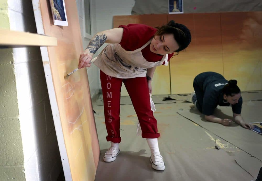 Johanna Lopez paints a canvas that will be one part of a two-story mural at the South Bay House of Correction in Boston. (Hadley Green for WBUR)