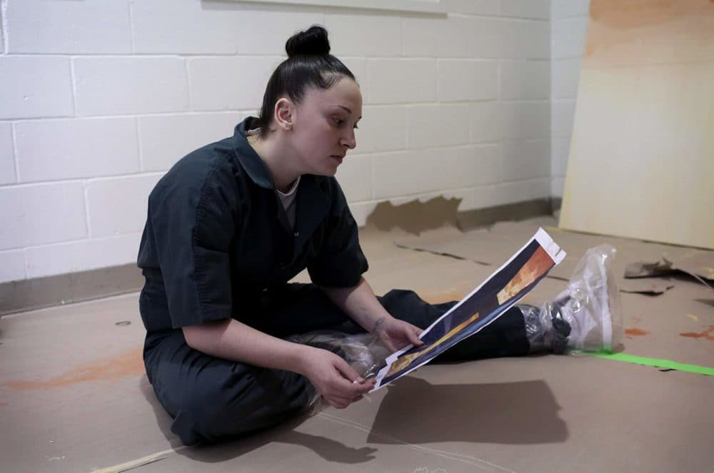 Allison Deshowitc looks at a reproduction of the mural the group is painting at South Bay House of Correction. (Hadley Green for WBUR)