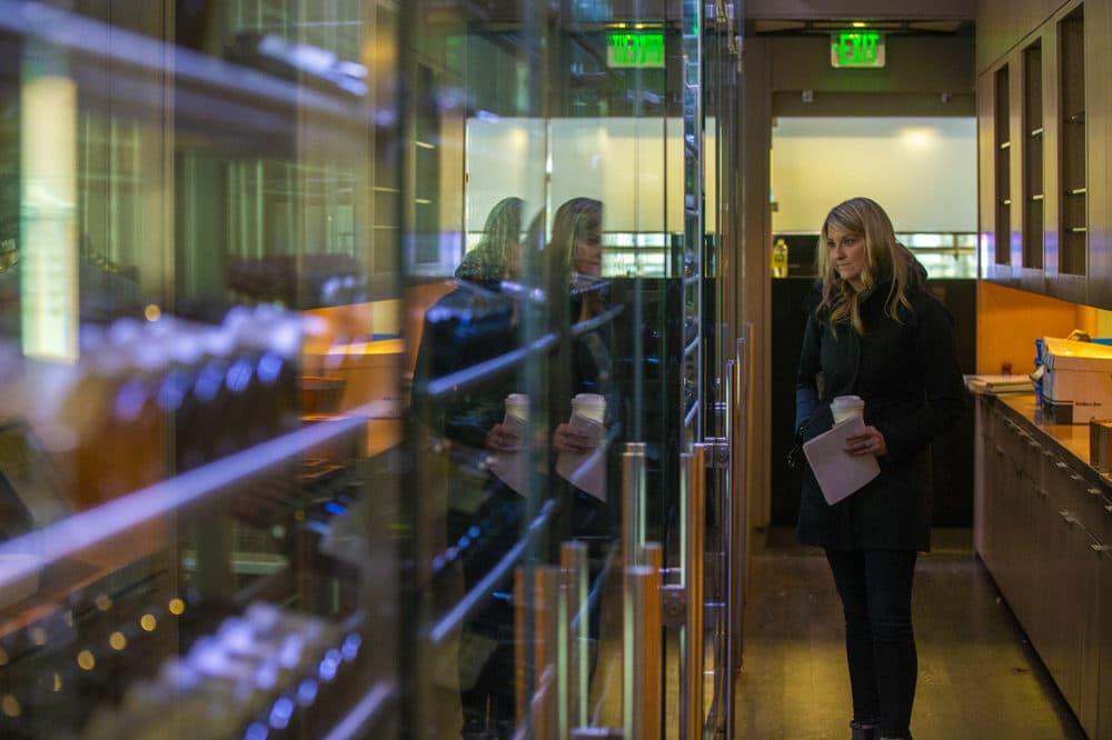 Meaghan Hughes of the restaurant Alchemy in Martha’s Vineyard peruses the large case of wine that runs the length of the hallway behind the restaurant. The wine was being auctioned the following day. (Jesse Costa/WBUR)