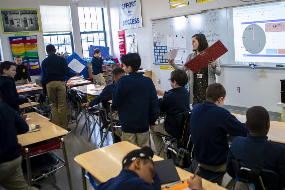 Boston Collegiate Charter School teacher Bridget Adam passes out work papers to her sixth grade math class. (Jesse Costa/WBUR)