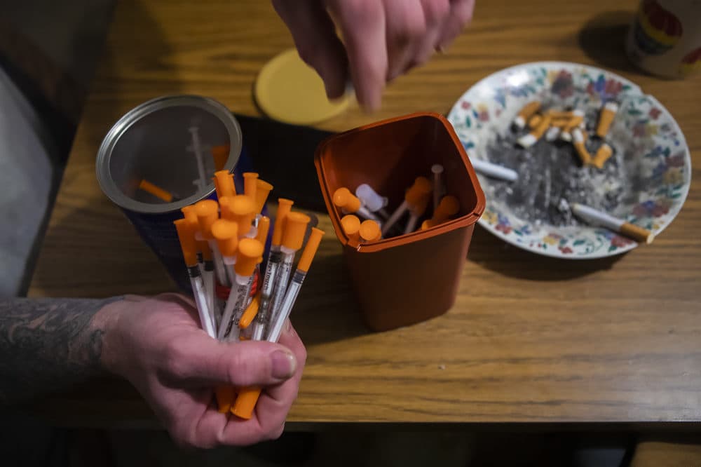 A drug user in Lewiston disposes used needles, to be exchanged for a new supply of needles. (Jesse Costa/WBUR)