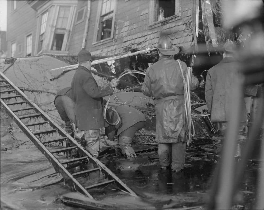 Firemen stand in thick molasses after the Boston molasses flood. (Courtesy of the Boston Public Library, Leslie Jones Collection)