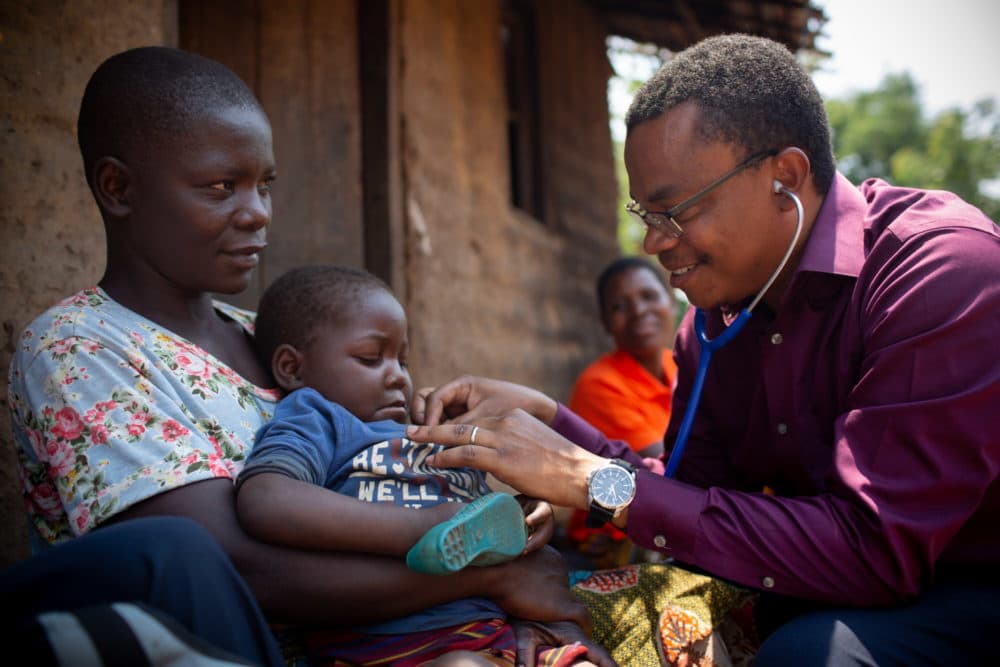 Dr. Dimitri Suffrin checks on HIV and malnutrition patient Agnes Makunda, 3, on September 28, 2018, while she is held by her mother, Margaret. Margaret walks to Ligowe Health Centre in Dzomodya Village, Malawi, at night and sleeps there, outside, with her four children; they are essentially homeless. (Courtesy Partners In Health)
