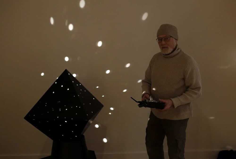 Sculptor John Powell stands with Otto Piene's diamond light robot as he helps with the installation process at the Fitchburg Art Museum. (Hadley Green/WBUR)