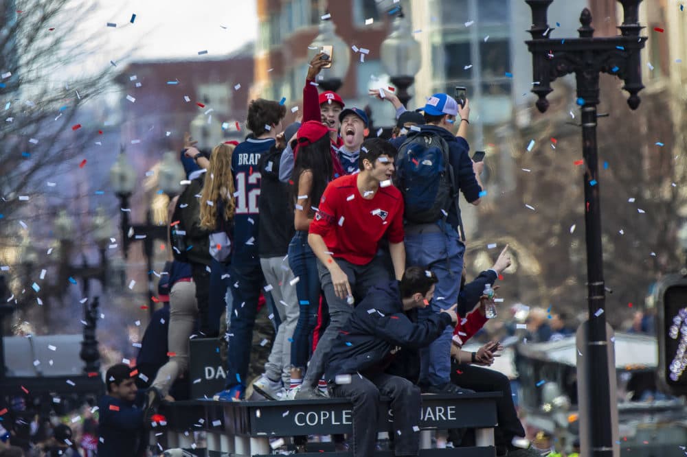 Patriots fans climb onto a bus shelter to get a better position to see the parade. They were promptly told by police to get down. (Jesse Costa/WBUR)