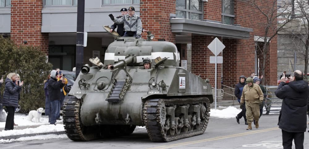 World War II tank gunner Clarence Smoyer waves from his perch seated on the hatch of a tank outside the Charlestown Naval Shipyard in Boston. (Charles Krupa/AP)