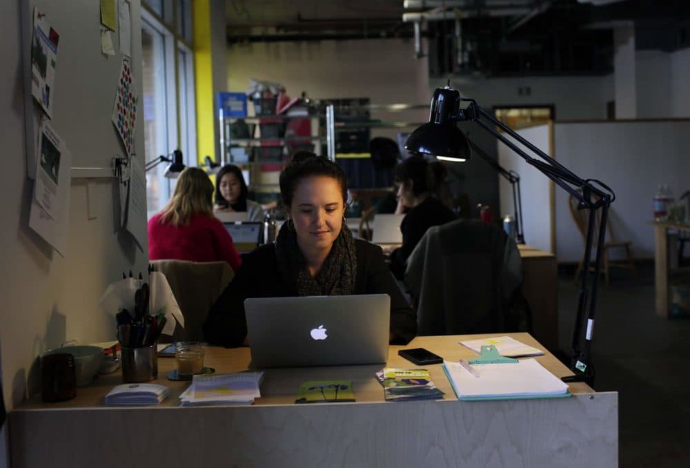 Ellen Shakespear, co-founder of Spaceus, works on her computer in the Spaceus storefront in East Cambridge. (Hadley Green for WBUR)