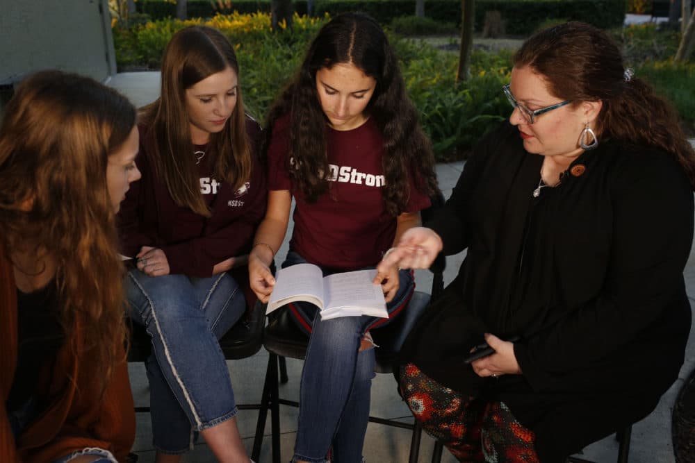 In this Wednesday, Jan. 16, 2019 photo, Brianna Jesionowski, from far left to right, Brianna Fisher and Leni Steinhardt sit during an interview, as journalism teacher Sarah Lerner, right, makes a point regarding the new book called &quot;Parkland Speaks: Survivors from Marjory Stoneman Douglas Share Their Stories.&quot; Students and teachers from the Florida school, where 17 died in  Feb. 2018 mass shooting, wrote the raw, poignant book about living through the tragedy. (Brynn Anderson/AP)