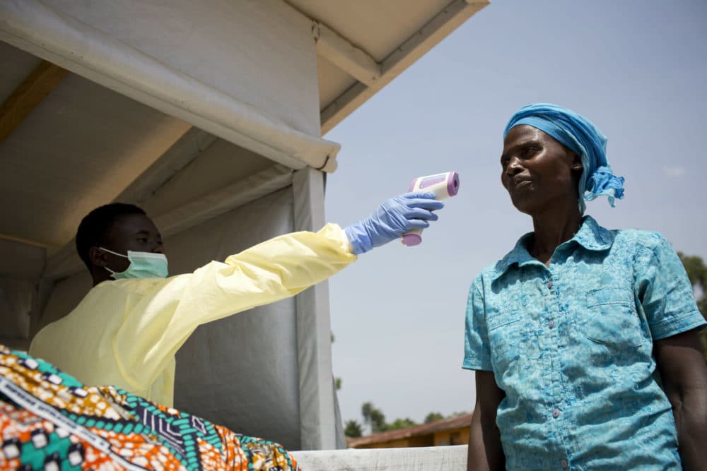 A patient has her temperature taken at the entrance to a health centre, as part of a triage system and Ebola prevention campaign that has been set up by the Swiss NGO Medair, in Mbau, near Beni in North Kivu province, in Congo Friday, Feb. 1, 2019. The deadly Ebola outbreak in eastern Congo marked six months on Friday. (Kate Holt/Medair via AP)