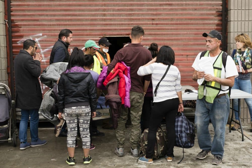 Migrants move their belongings into a temporary shelter provided by the Mexican government. The shelter is an old warehouse, without any running water or bathrooms. Co-author Karen Pita Loor is pictured behind the table, on the right. (Courtesy Jozef Staska)