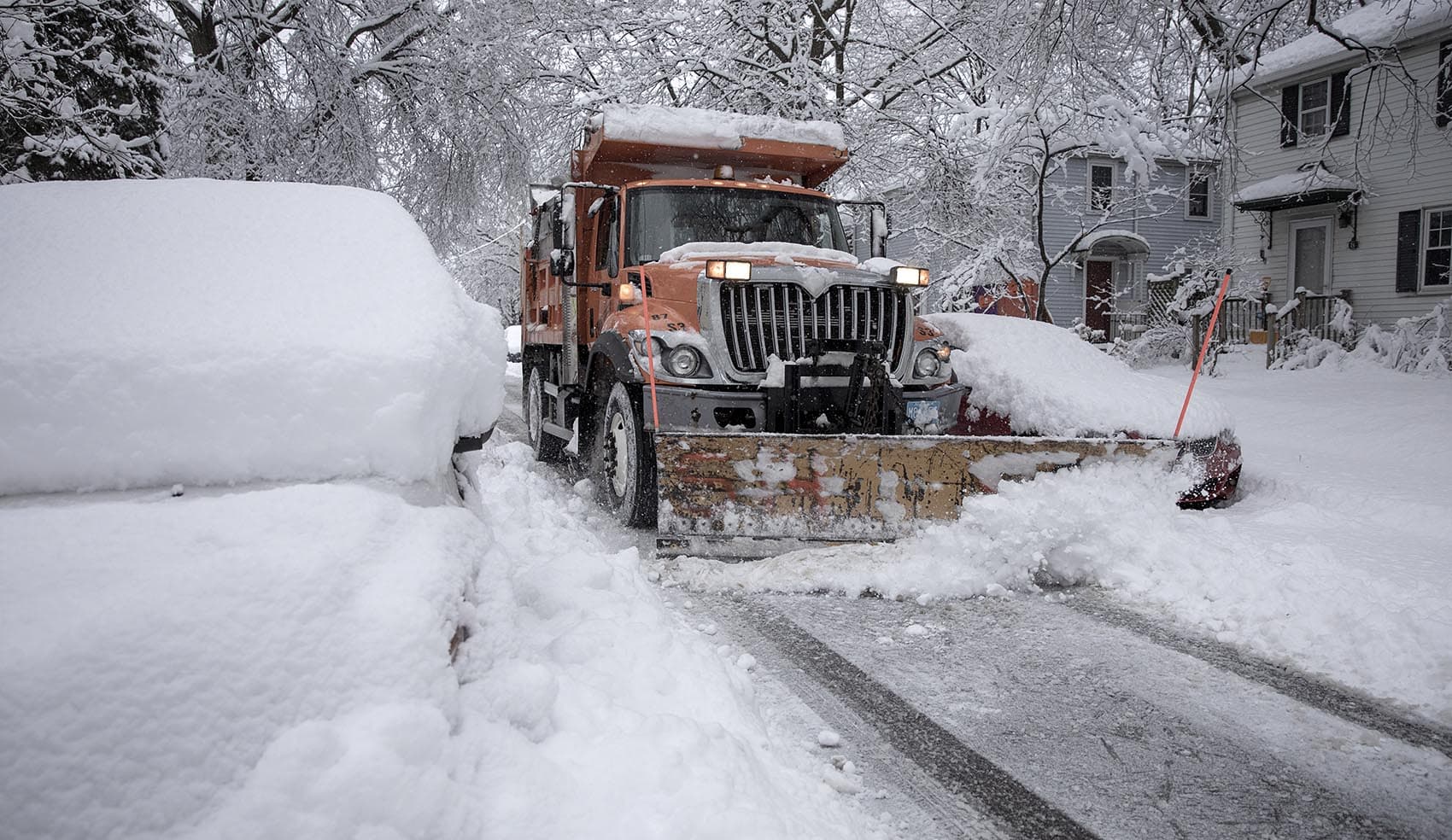 A snow plow threads its way along a Cambridge street clearing overnight snow. (Robin Lubbock/WBUR)