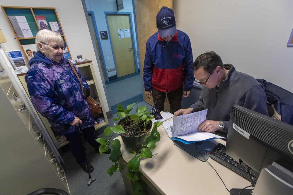 Patient experience coordinator Chris Riga looks into a billing issue for another veteran and the man's wife at the VA in Northampton, Mass. (Jesse Costa/WBUR)