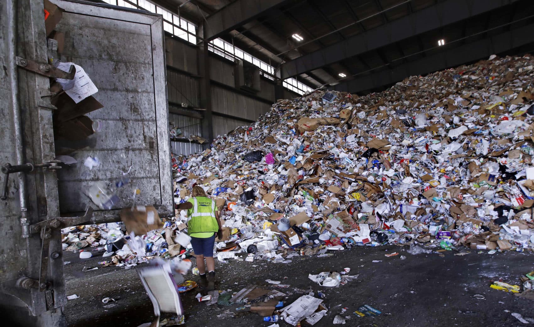 In this 2018 file photo, a trailer door is opened on a truck filled with unsorted recyclable refuse as it is offloaded and added to a giant pile in a processing building at EL Harvey &amp; Sons, a waste and recycling company in Westborough. (Charles Krupa/AP)