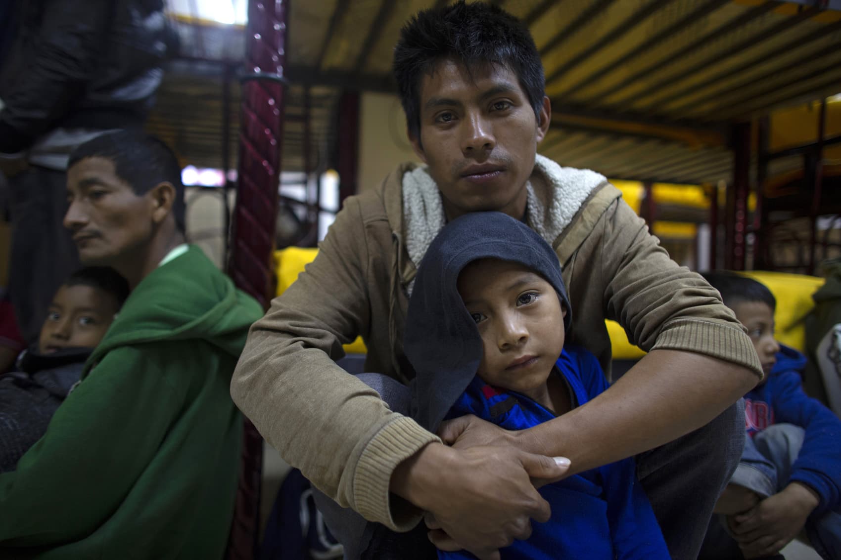 Abraham, 7, sits on the floor with his father, Miguel Martin, 27, at the San Juan Bosco migrant shelter, in Nogales, Mexico. Miguel left behind his wife and another son in hopes of getting enough work to buy some land in their hometown since they are now practically homeless in Guatemala. (Dario Lopez-Mills/AP)