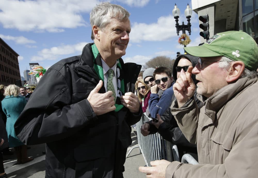 Massachusetts Gov. Charlie Baker, left, displays his green tie to a spectator at the start of the St. Patrick's Day parade. (Steven Senne/AP)