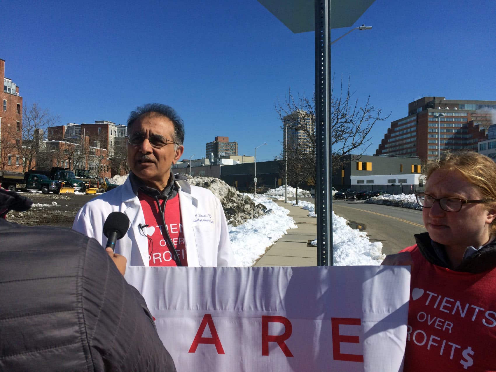 Vikas Saini, left, speaks with On Point host Meghna Chakrabarti at a protest against high insulin prices at pharmaceutical company Sanofi's offices in Cambridge, Mass. (Anna Bauman/On Point)