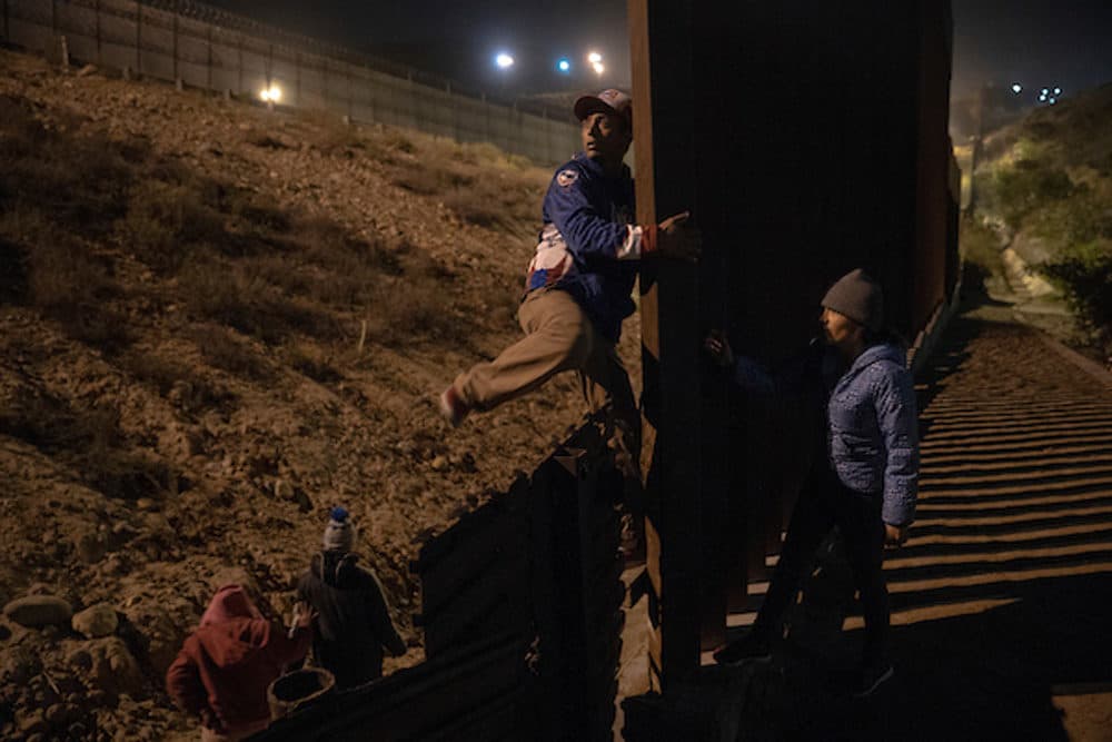 Migrants scope out and try to find a place to cross the U.S. - Mexican border wall near the beach in Tijuana, Mexico, on December 16, 2018. Some attempt to dig under the wall, while others pass over it. (Kitra Cahana/MAPS)