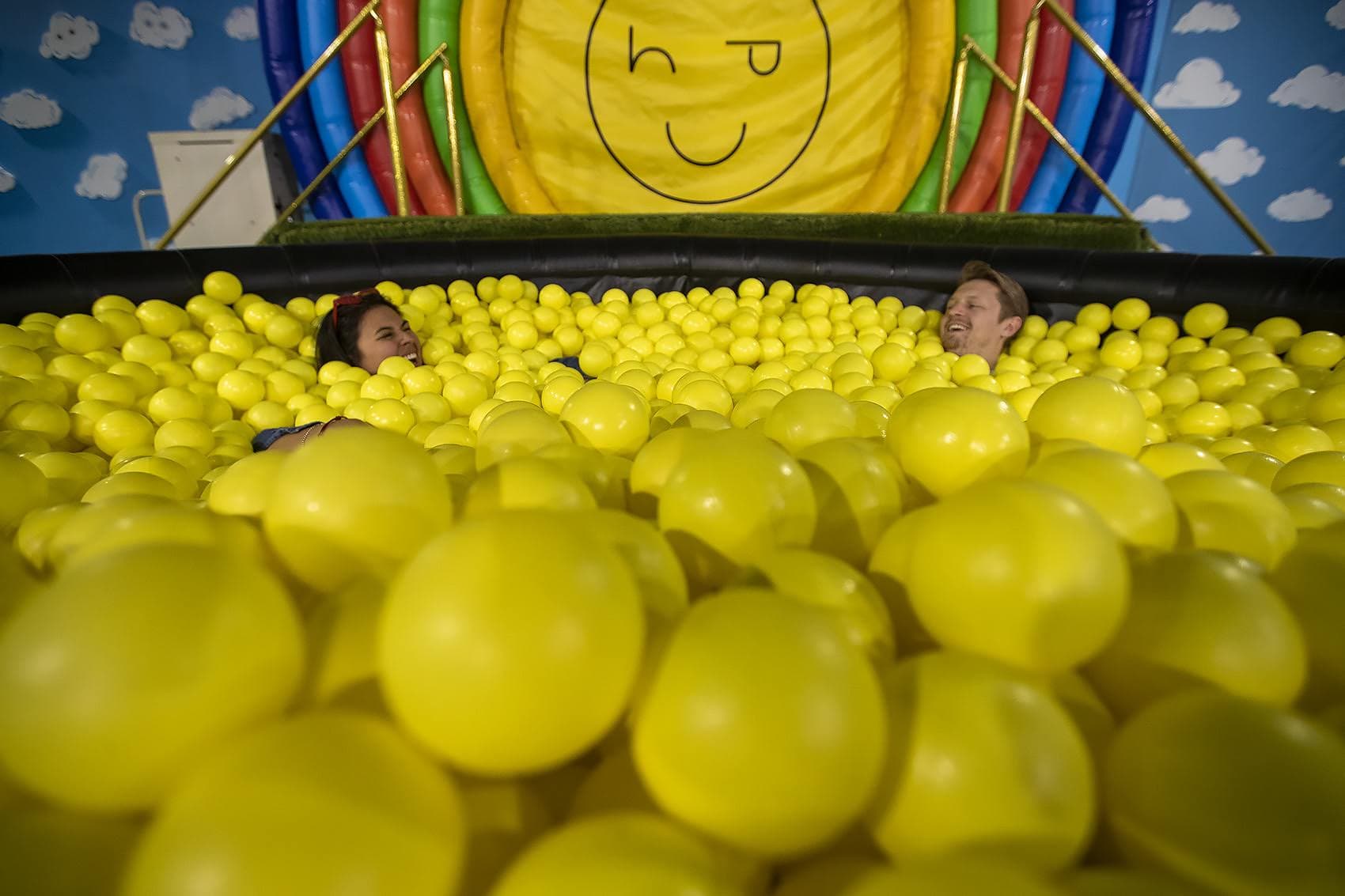 Madison Munoz and Riley Bates enjoy themselves in the pool of yellow balls at “Happy Place.” (Jesse Costa/WBUR)
