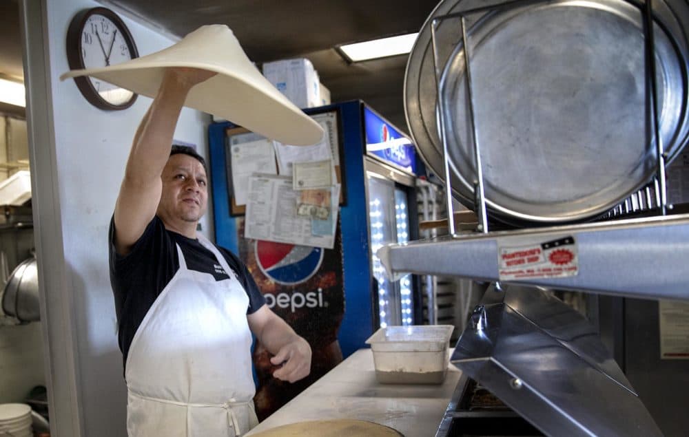 Boli Matute, owner of Boli’s Pizza, tosses dough in the air. (Robin Lubbock/WBUR)