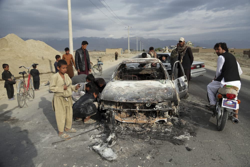 Afghans watch a civilian vehicle burnt after being shot by US forces after an attack near the Bagram Air Base, north of Kabul, Afghanistan, Tuesday, April 9, 2019. (Rahmat Gul/AP)