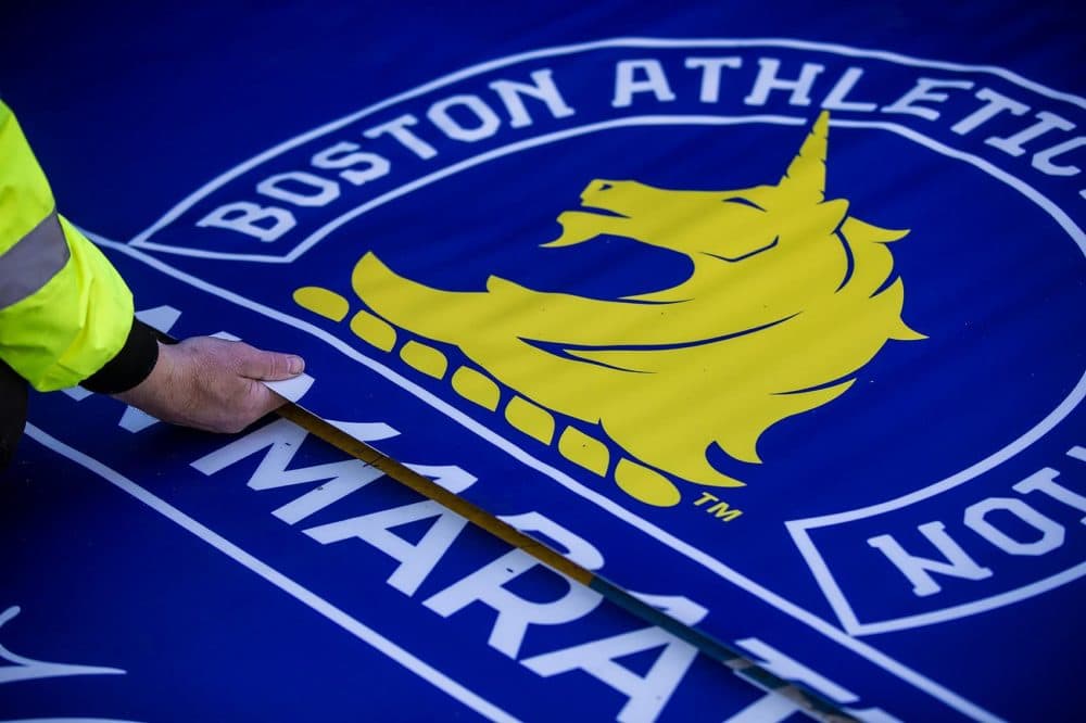 Workers from Accurate Graphics lay down the finish line on Boylston Street in Copley Square for the 2019 Boston Marathon. (Jesse Costa/WBUR)