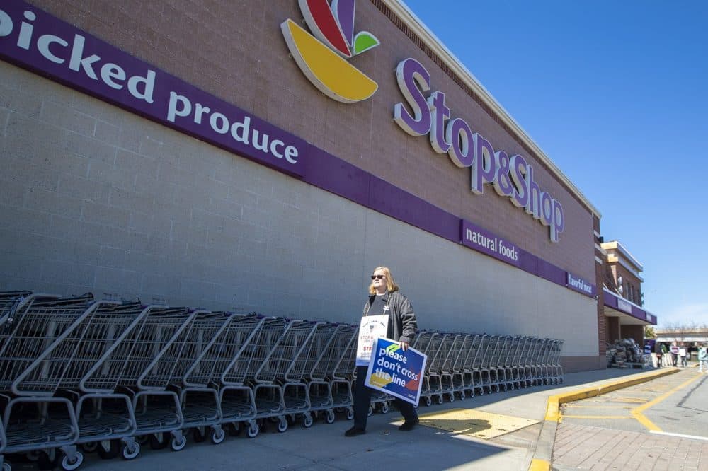 A striking Stop & Shop worker walks in front of the main entrance of the Somerville location on McGrath Highway on Thursday, when the strike began. (Jesse Costa/WBUR)