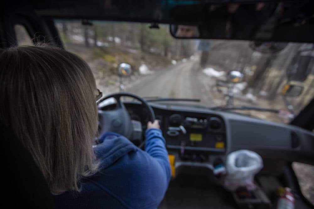 Joanne Deady drives her bus around a bend of an unpaved Thompson Road in Colrain on her route after the school day. (Jesse Costa/WBUR)