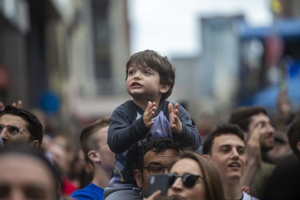 A young spectator cheers as the elite men race toward the finish line. (Jesse Costa/WBUR)