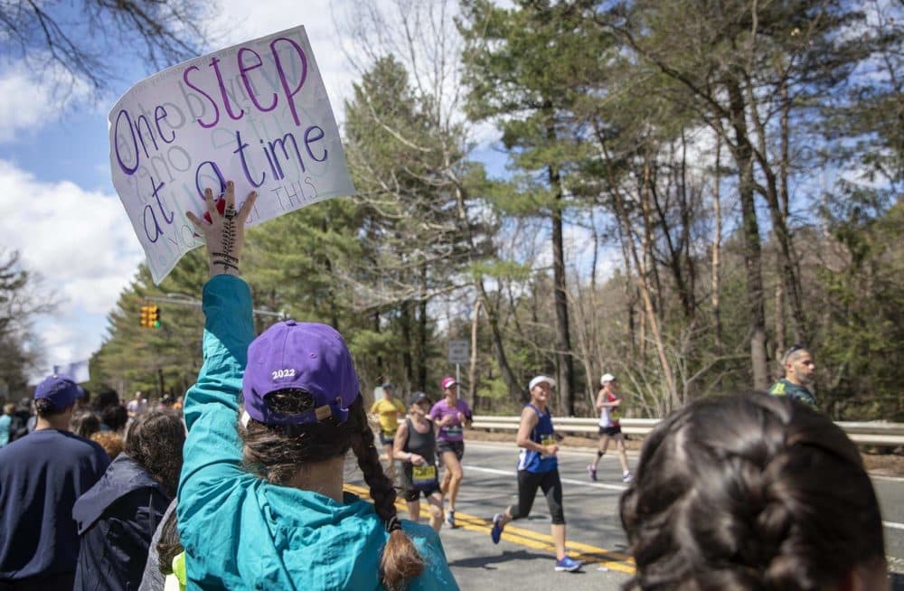 A woman holds up a sign to encourage runners through the Wellesley “scream tunnel.” (Robin Lubbock/WBUR)